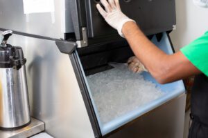 employee scooping ice from ice cube making machine