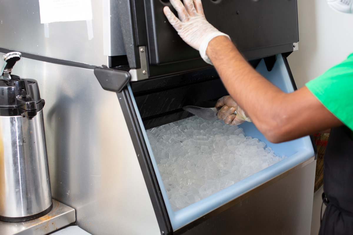 Employee scooping ice from ice cube making machine