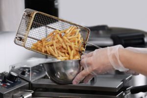 chef pouring french fries from deep fryer into bowl