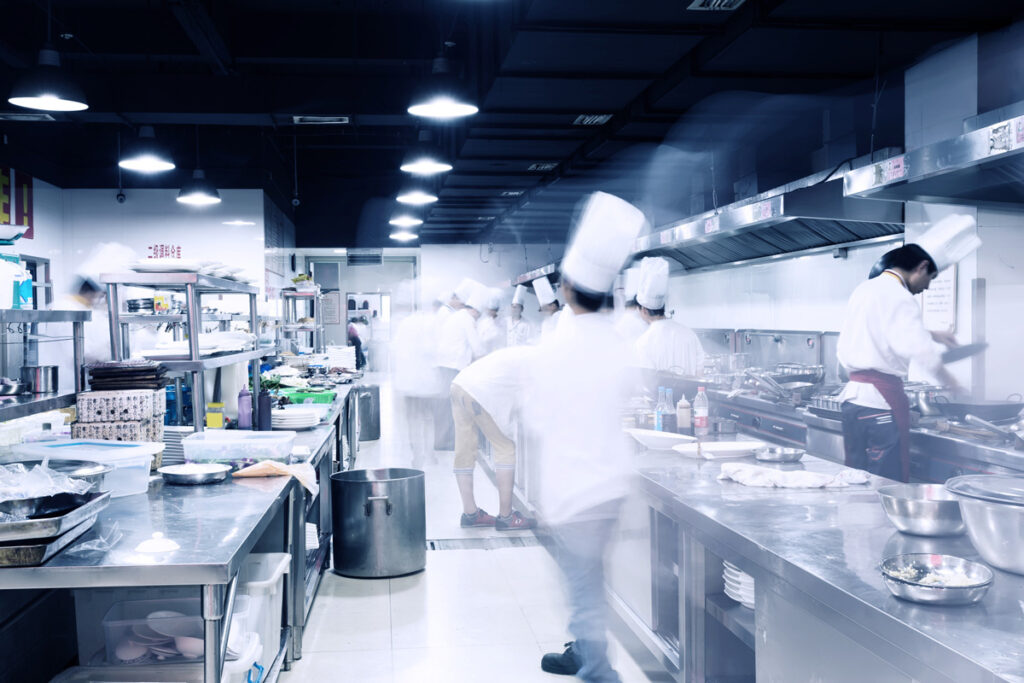 Hotel commercial kitchen depicting passage of time through motion blur of busy chefs