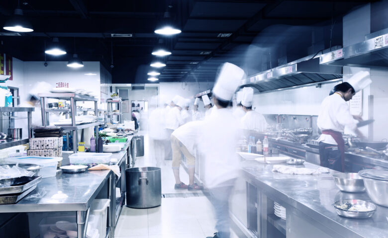 Hotel commercial kitchen depicting passage of time through motion blur of busy chefs