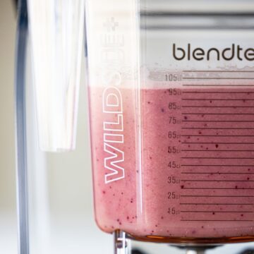 Top half of blender container filled with blended pink beverage