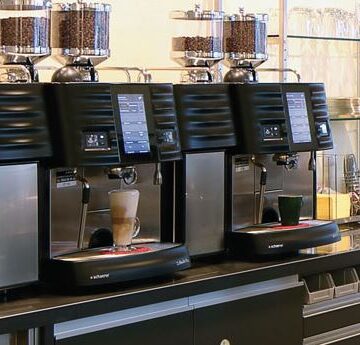 Barista making coffee in coffee shop with 3 automatic espresso machines