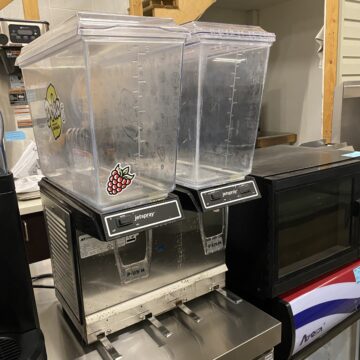 Angled view of beverage dispenser , metal bottom and clear dispensers with lemonade sticker