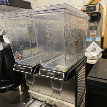 Front view of beverage dispenser , metal bottom and clear dispensers with lemonade sticker
