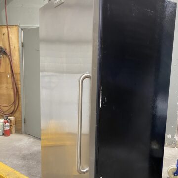 Front side view of stainless steel front door and black sides upright commercial freezer