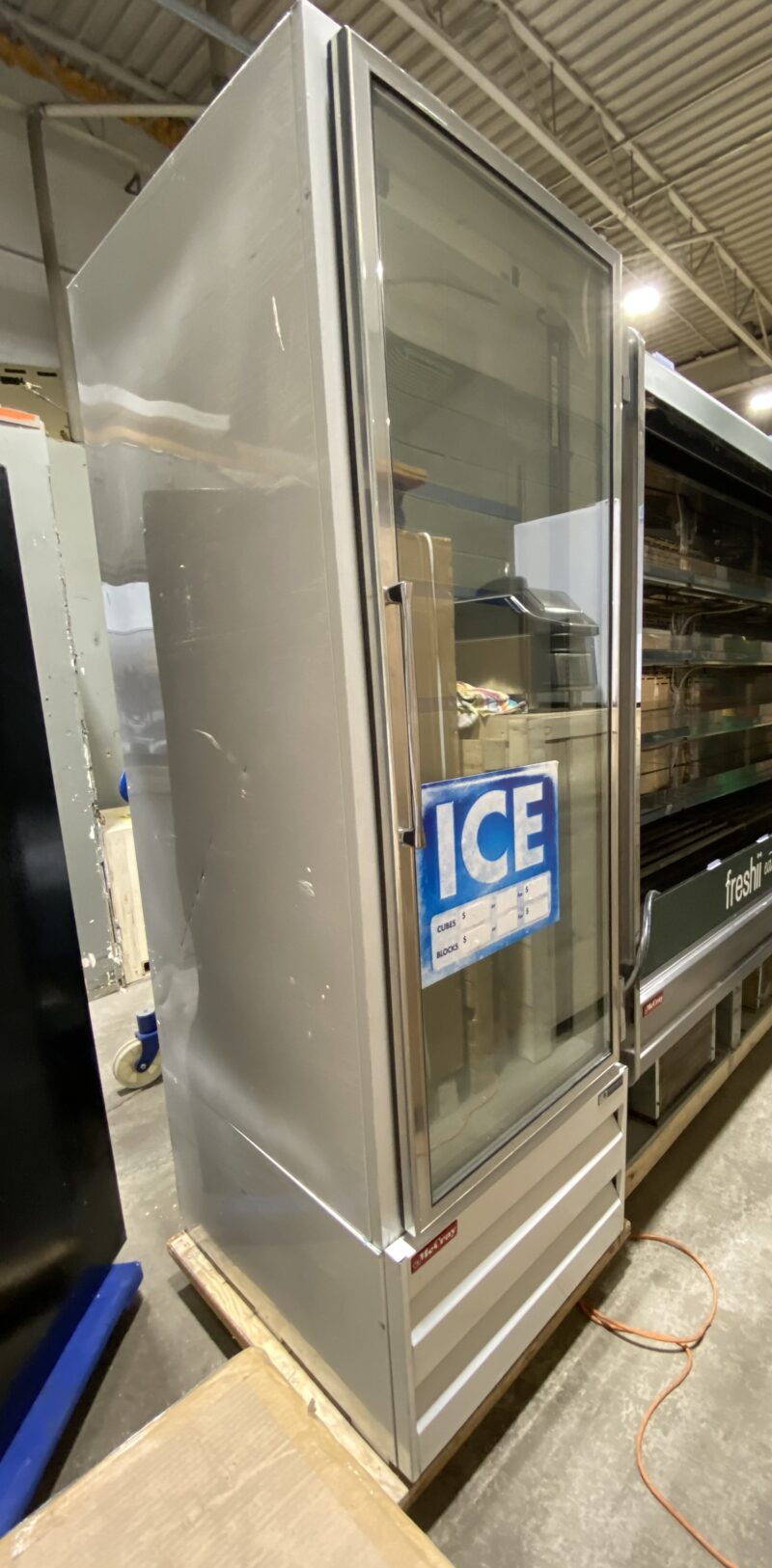 Front side view of upright commercial glass door ice freezer