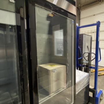 Front side view of commercial upright 1 glass door freezer showing 1 box on shelf inside