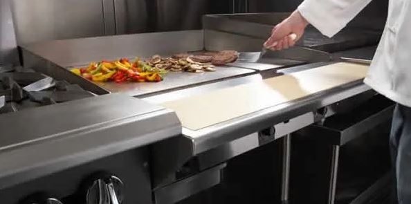 chef using a flat top grill in kitchen
