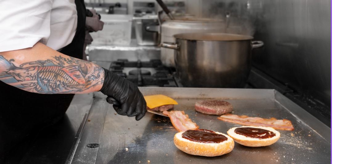 chef cooking burgers of flat grill