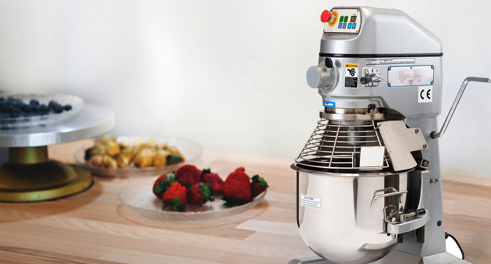 Planetary mixer on a table with fruit on a white background